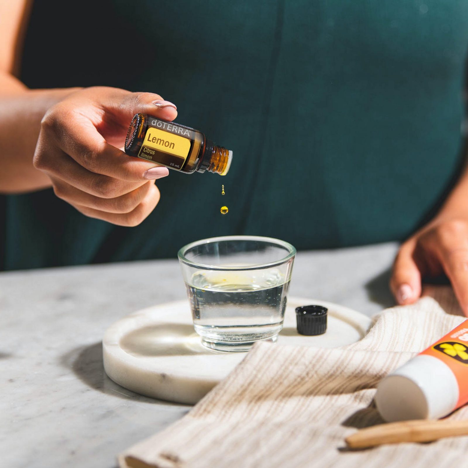 lady putting drops of essential oils into a glass